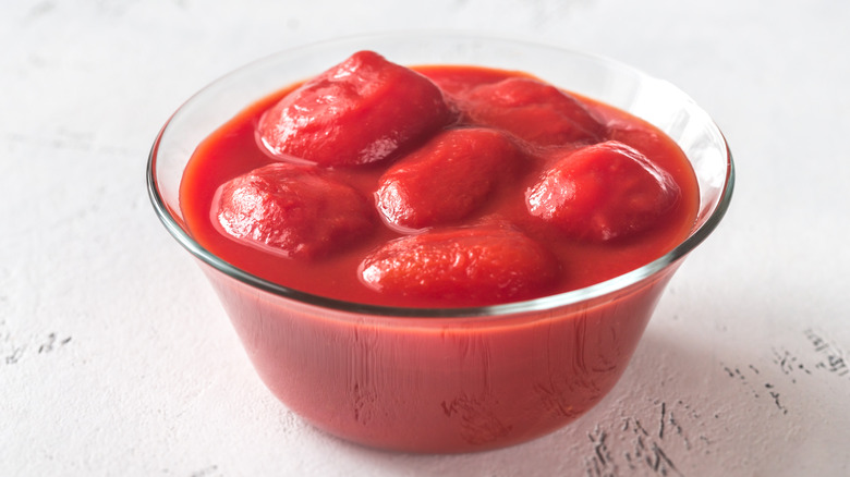 canned whole tomatoes poured into a glass bowl