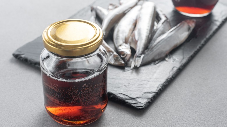 A jar of fish sauce and fish on slate