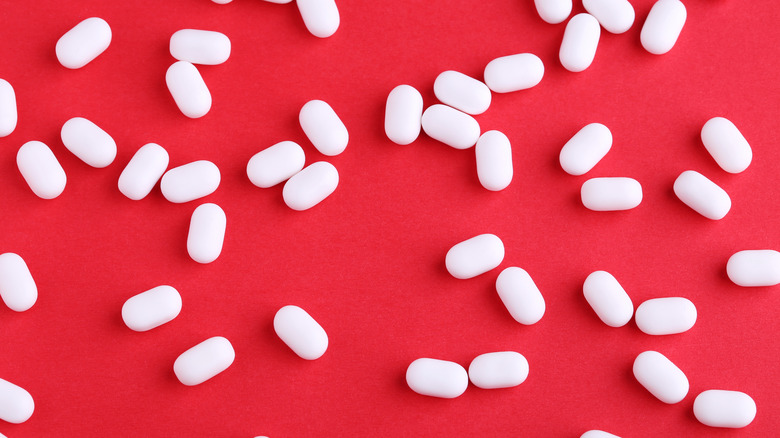 Tic Tac candy scattered on red background