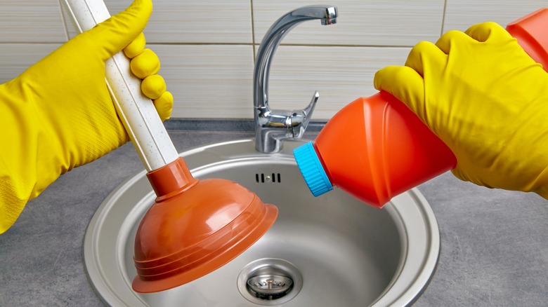 Person holding plunger over sink