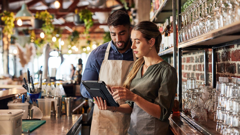 Two restaurant workers looking at a tablet