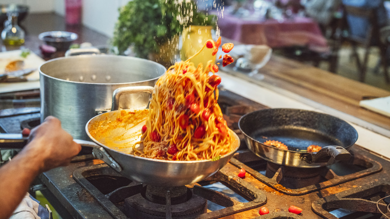 Spaghetti finishing cooking in tomato sauce