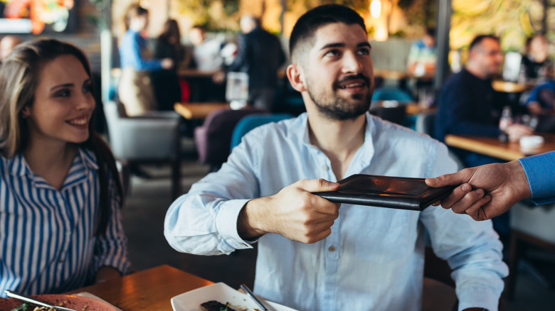 man handing a server the check after a meal