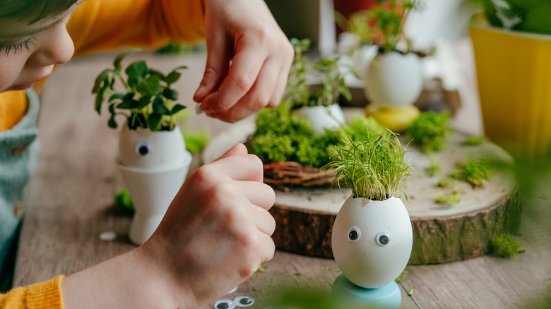 Child decorating eggshells with grass 