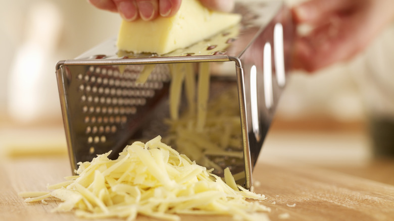 hand grating cheese on a grater laid sideways