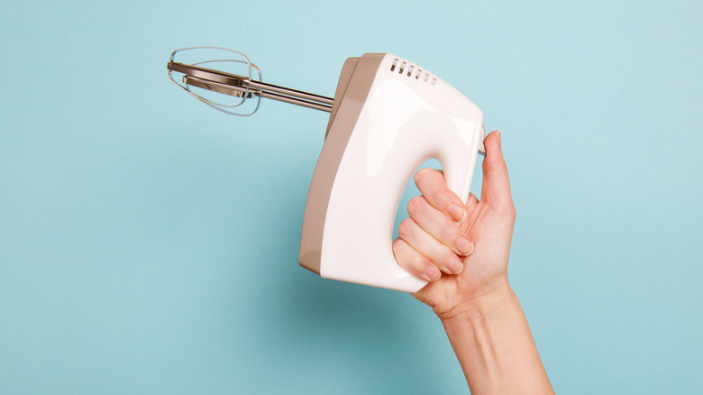 A person holds an electric beater