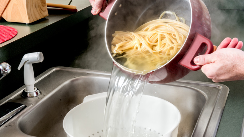 Fettuccine being strained in white colander