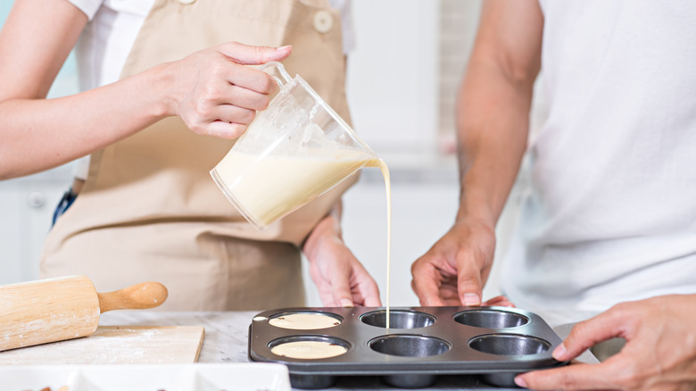 Woman pouring egg mix into muffin tin