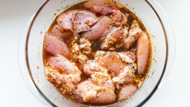 Chicken marinating in clear bowl