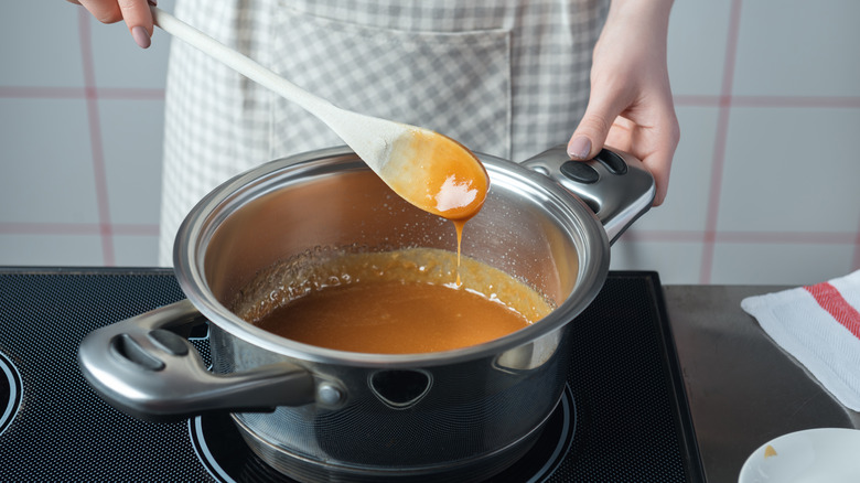 woman making caramel in pot on stove