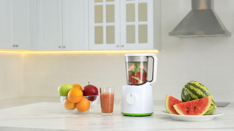 Whole fruits, blender, and smoothie on kitchen island