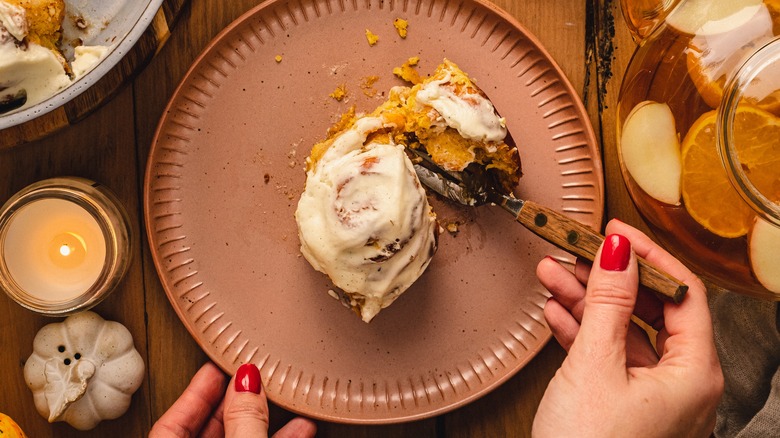 Cutting a glazed pumpkin cinnamon roll