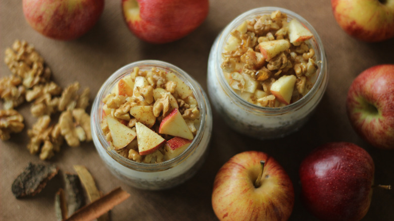 Overnight oats with chia seeds in a jar surrounded by apples