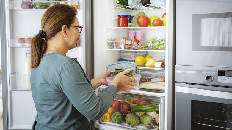 woman putting fruit in fridge