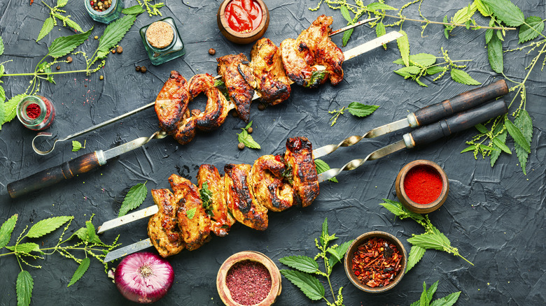 double skewers with meat on surface with herbs