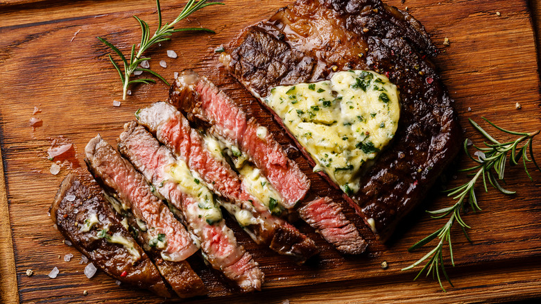 Seared steak with compound butter on a chopping board