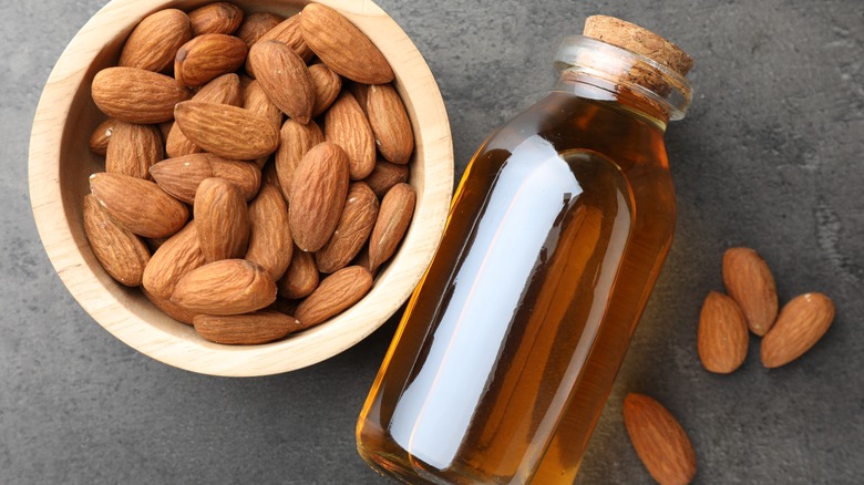 Almonds in a bowl beside bottle of almond extract