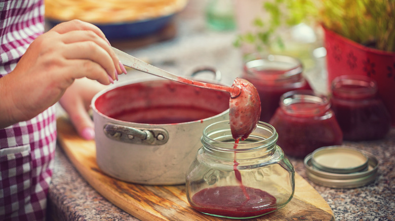 Woman ladling homemade jam into a jar