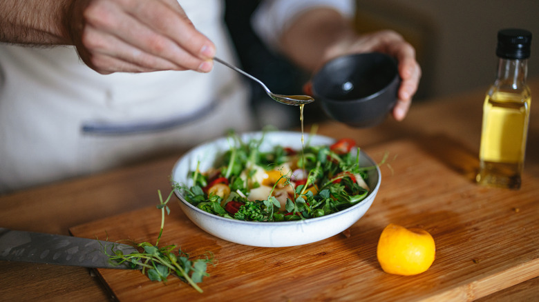 adding homemade dressing to salad