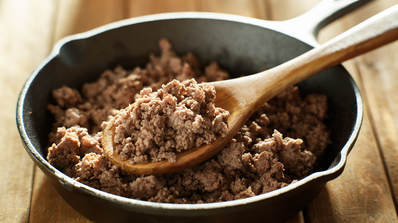 ground beef in skillet, wooden spoon