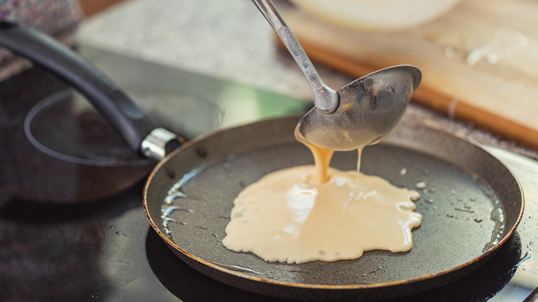 pouring crepe batter in pan