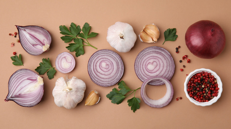 red onions next to herbs, garlic, and juniper berries