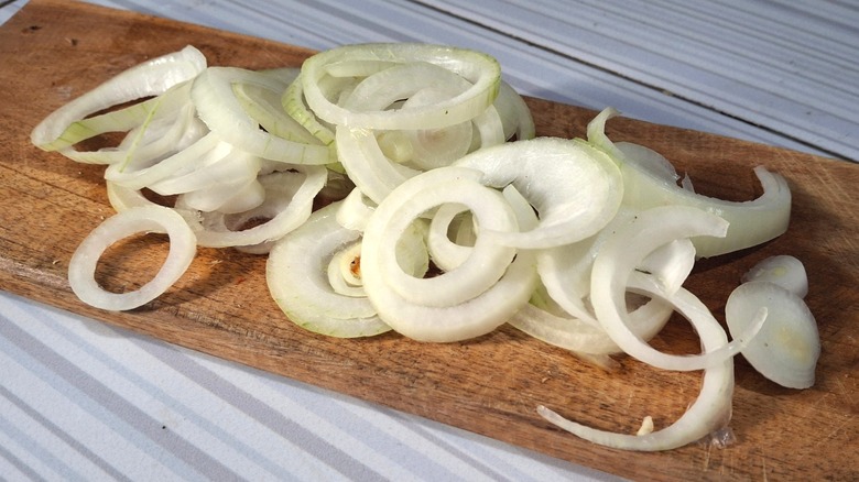 raw white onion rings on cutting board