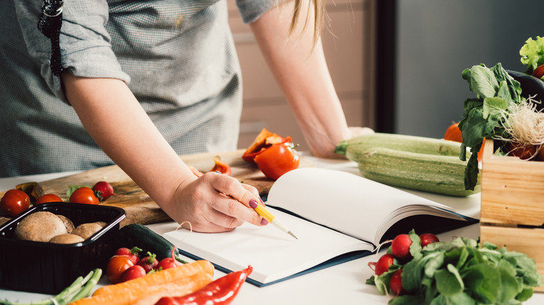 Woman writing down recipe while cooking