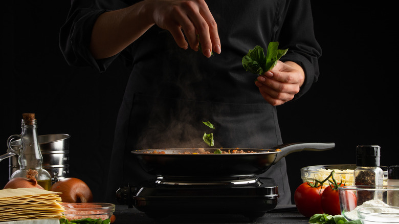 Chef adding herbs to sauce