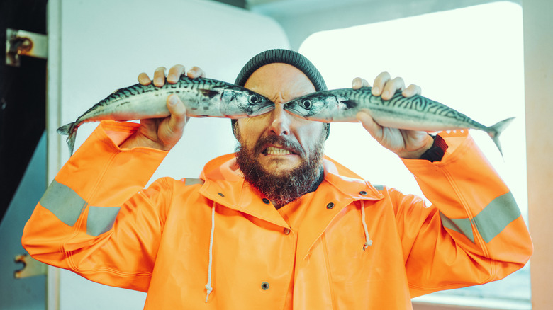 A fisherman holding up a pair of fresh fish.