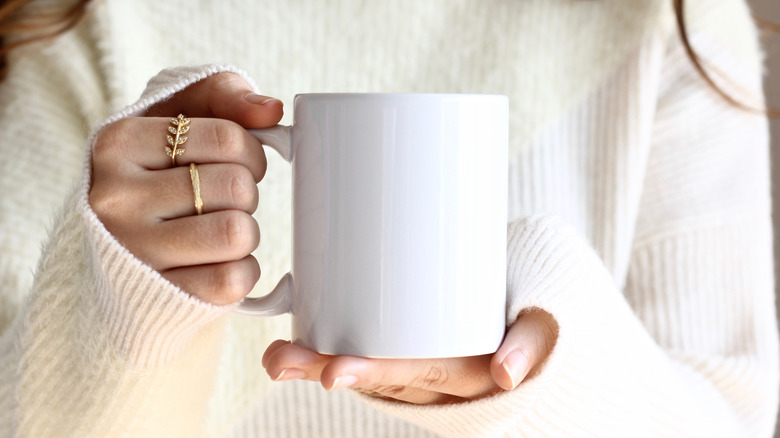 Woman holding mug wearing a white sweater