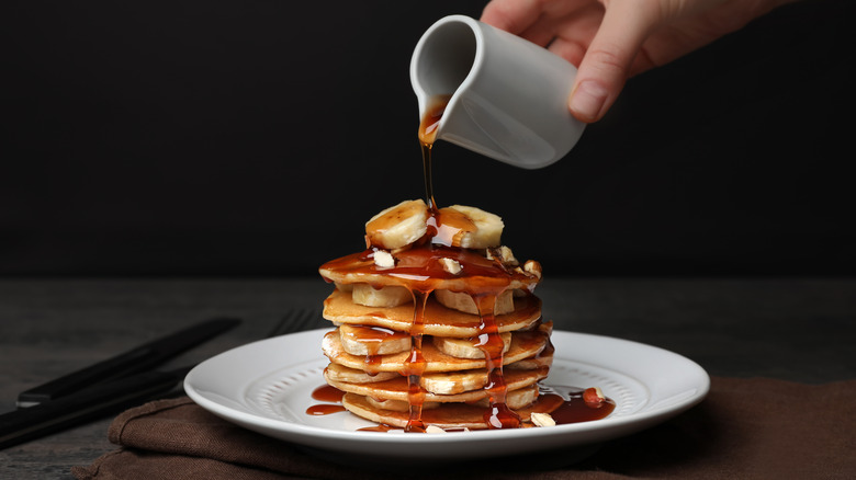 Pouring syrup onto banana pancake stack