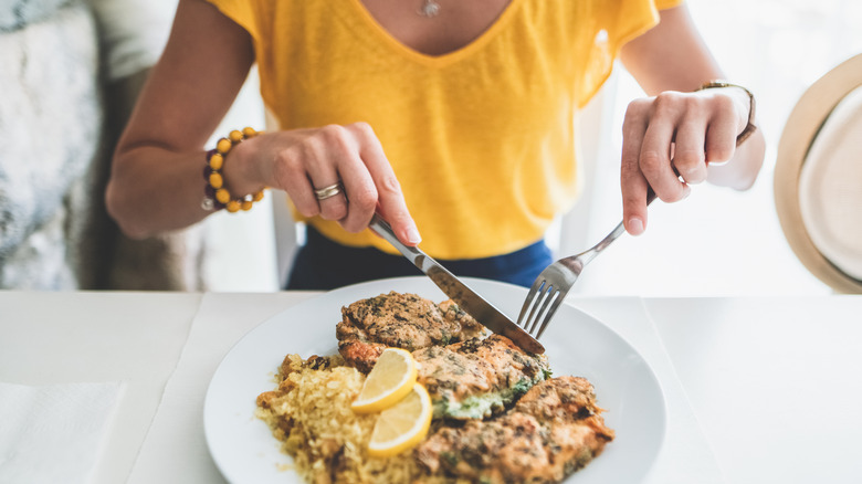 woman cutting food on plate