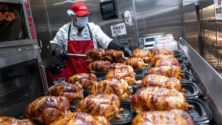 Costco worker preparing rotisserie chickens