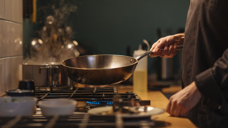 Person holds a pan on stovetop