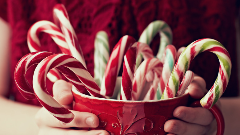 person holding cup of candy canes