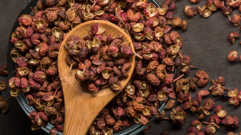 A spoonful of Szechuan peppercorns scooped out of bowl