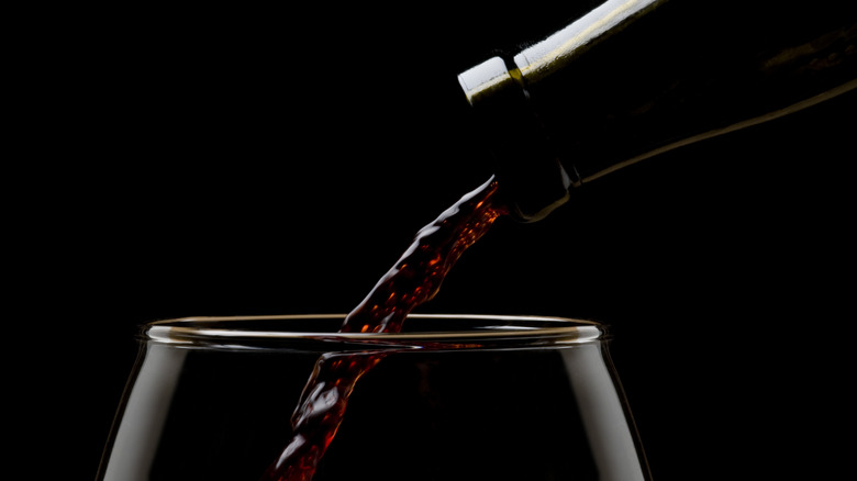 Red wine being poured into a wine glass up close