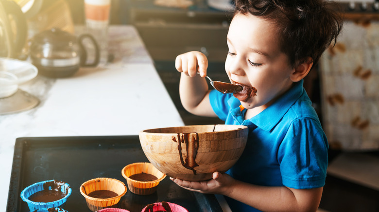 Child filling cupcake molds