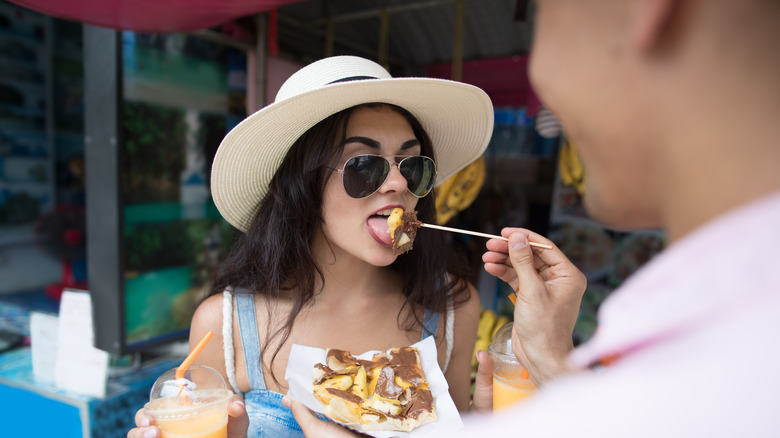 man feeding woman in hat