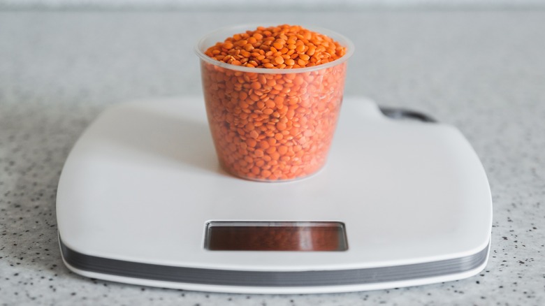 Measuring cup with lentils on scale