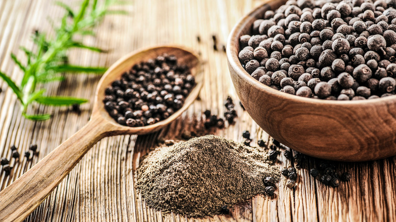 whole and ground peppercorns on wood surface