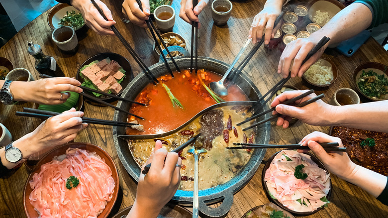 Large group dining on hot pot with chopsticks