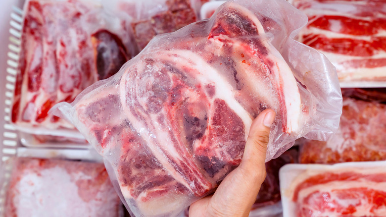 hand picking wrapped frozen pieces of beef out of freezer