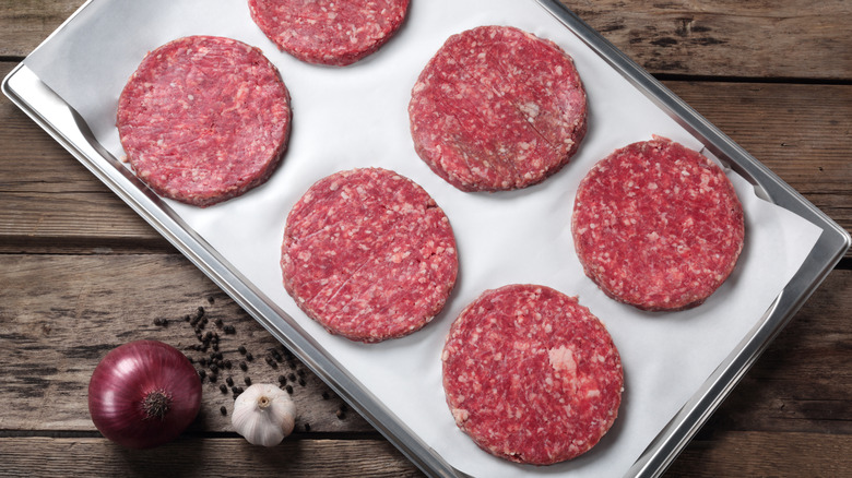 raw beef patties on baking dish