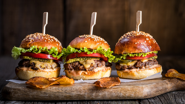 Three burgers on wooden board