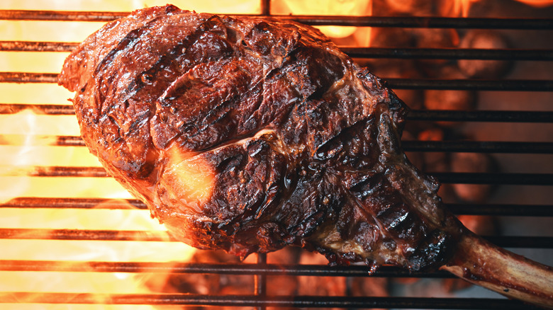 tomahawk steak grilling over fire