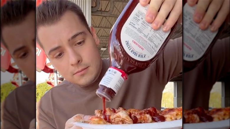 man drizzling BBQ sauce on pizza