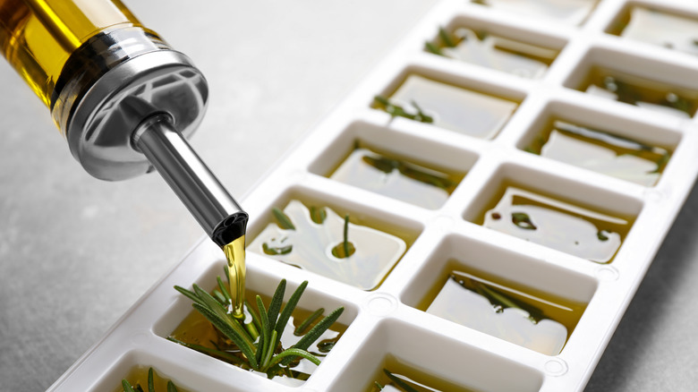 Pouring oil into herb-filled ice cube tray