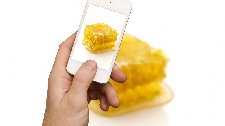 a person taking a picture of honey comb